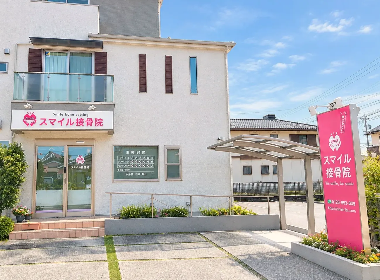 スマイル接骨院の外観。ピンクの看板と入口